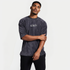 Sportliches Herrenmodel im Elite Club Oversized Cord T-Shirt Anthrazit mit weißem Brustlogo, Arm locker überkreuzt, moderne Streetwear Studioaufnahme