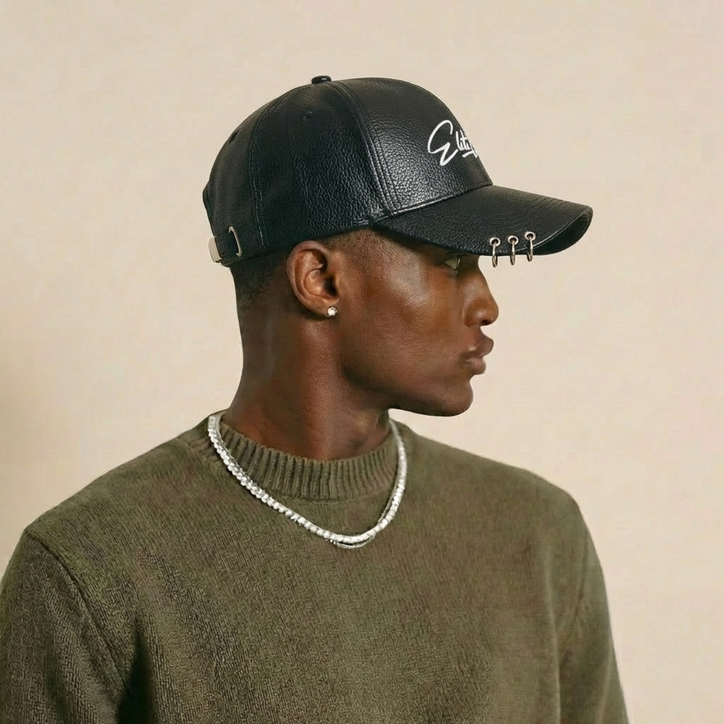 Athletisches männliches Model trägt schwarze Elite Club Leder-Cap mit strukturierter Oberfläche und Metallringen am Schirm, Seitenansicht vor neutralem Studiohintergrund.